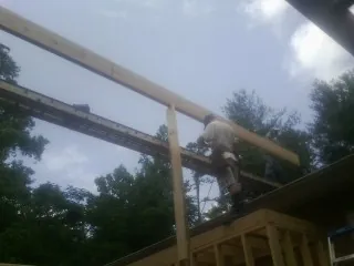 Carpenter setting a ridge beam over a new addition frame — Ice Dam Removal by Roofing Brothers in Pinola
