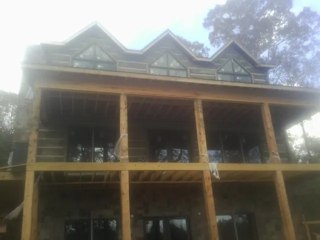 Dormers and porch framing on a large log home under construction — Roof Coating work by our crew in Pinola