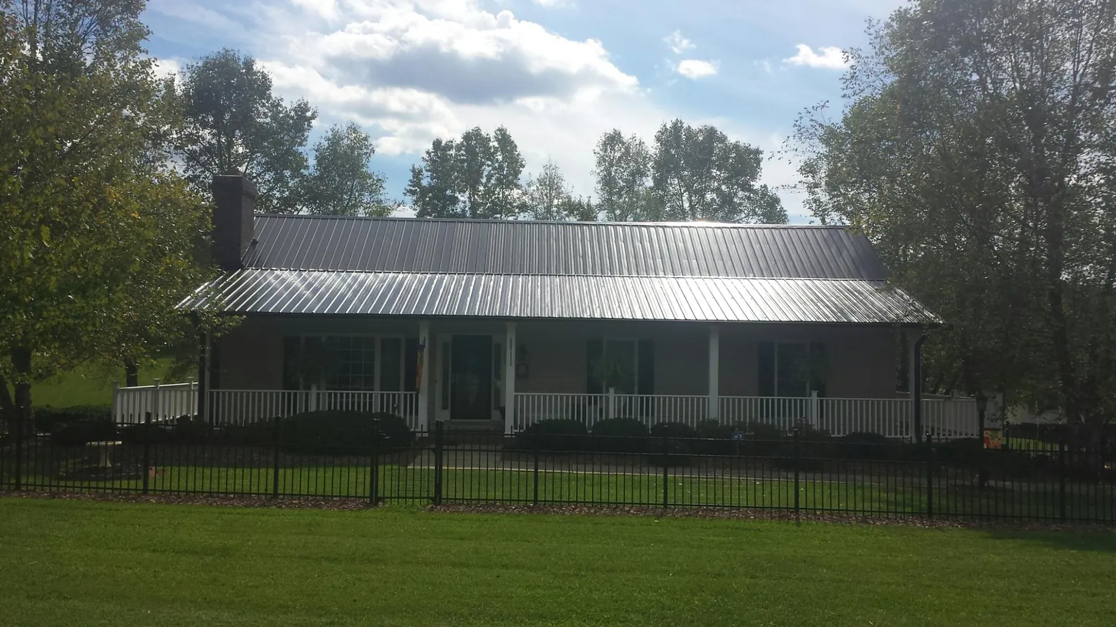 Gray metal roof on a brick ranch with a full width front porch — Gutter Guard Installation work by our crew in Pinola