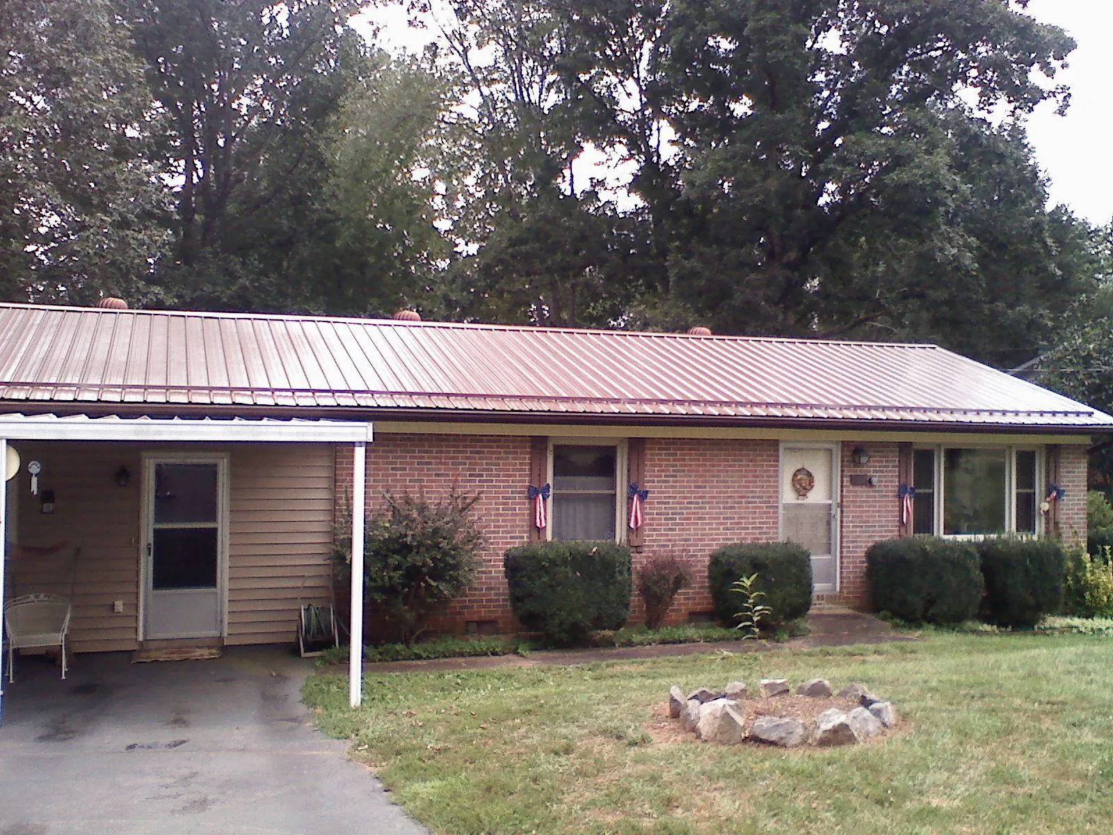 Bronze metal roof and carport on a brick ranch home — Roof Repair work by our crew in Pinola