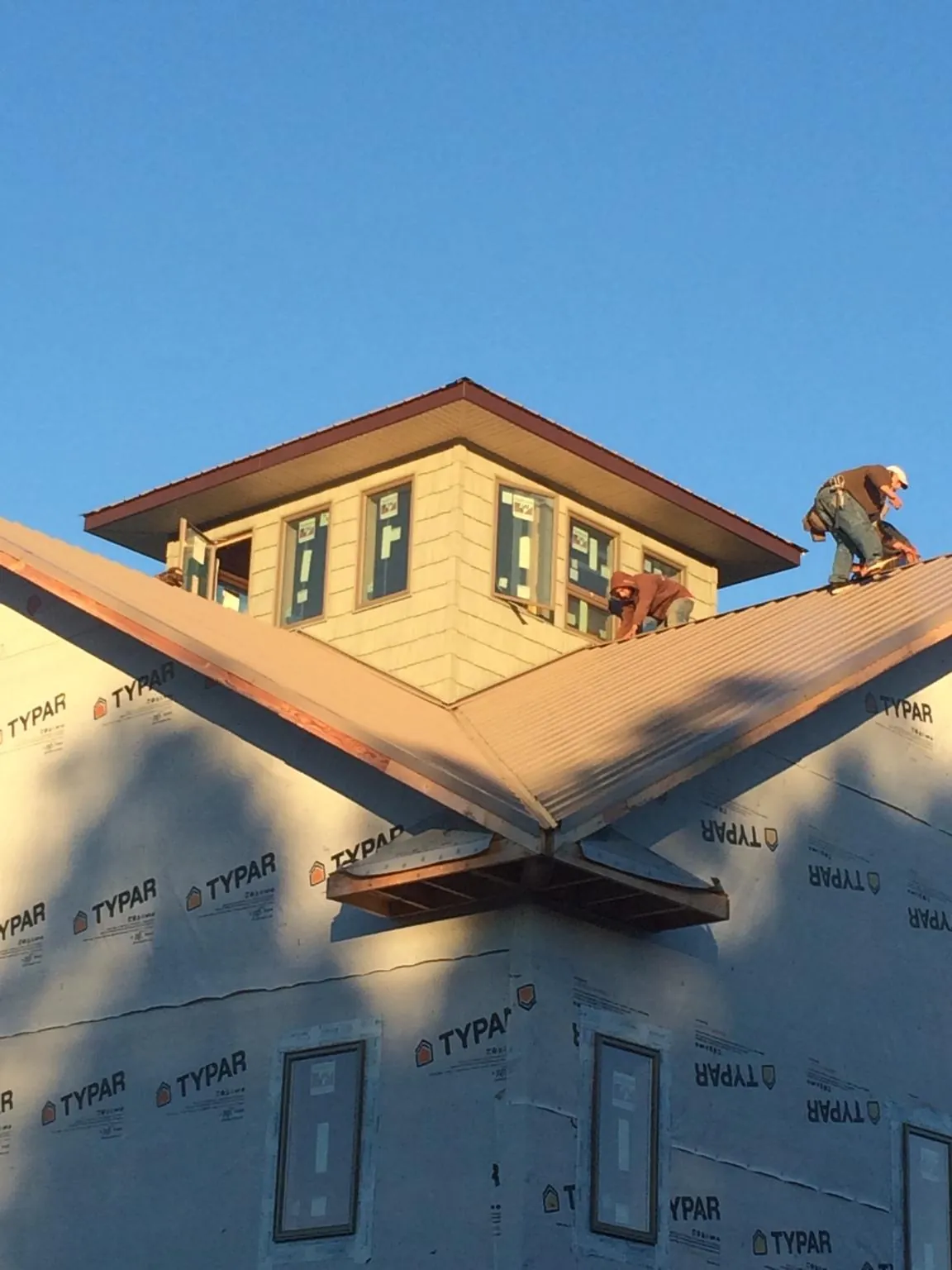 Roofers working around a rooftop cupola on a new metal roof at sunset — Roof Waterproofing in Pinola by Roofing Brothers